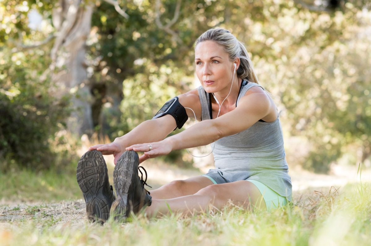 Middle aged women sitting in a park and stretching legs