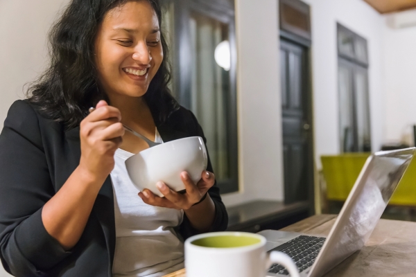woman enjoying the present moment eating in front of a computer